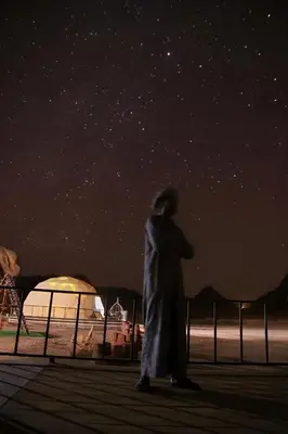a man standing on a pier under a starry sky at Wadi rum Hi camp in Wadi Rum