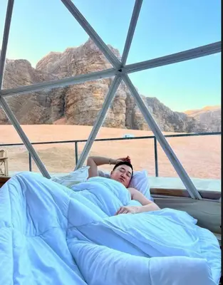 a woman laying in bed on a boat at Wadi rum Hi camp in Wadi Rum