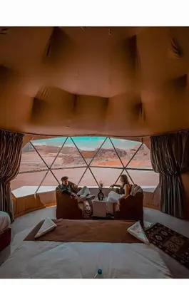two people sitting in chairs in a room with a large window at Wadi rum tenda camp in Wadi Rum