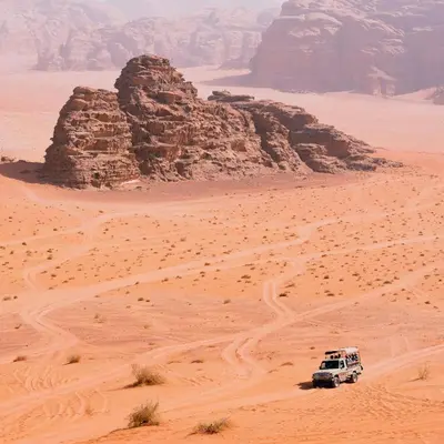 a white truck driving through the desert at Wadi rum lona camp in Wadi Rum