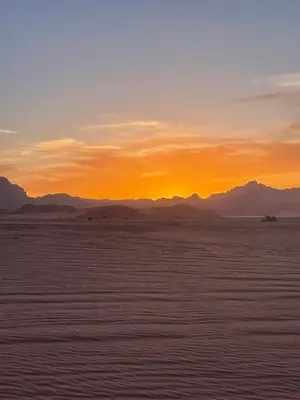 a sunset in the desert with mountains in the background at Nomads Heaven in Disah