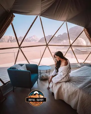 a woman sitting on a bed in a yurt at ROYAL SAVOY lUXURY CAMP in Wadi Rum