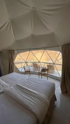 a bedroom with a bed and a large window at NOVA lUXURY CAMP in Wadi Rum