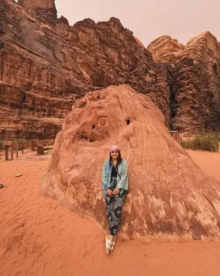 a woman standing in front of a rock formation at NOVA lUXURY CAMP in Wadi Rum