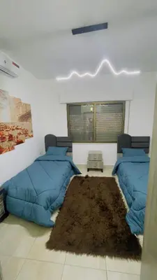 a room with two blue beds and a rug at شقة مفروشة في طبربور in Amman