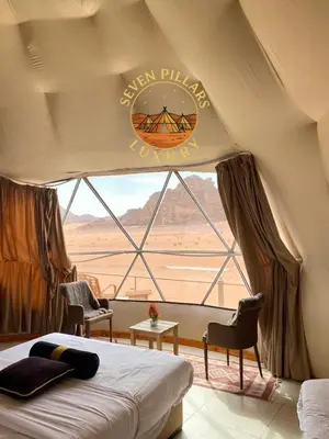 a bedroom with a bed and a window with a sign at Seven Pillars Luxury Camp in Wadi Rum