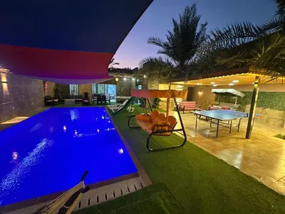 a swimming pool in a house with a table and a ping at Al Zain Chalet - Private Pool in Al Kafrayn