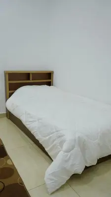 a bed with a white comforter on top of it at Al Zain Chalet - Private Pool in Al Kafrayn