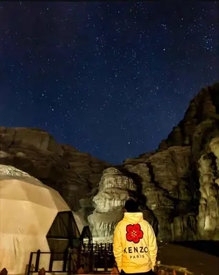 a person in a yellow jacket looking at the stars at Noor Luxury Camp Wadi Rum in Wadi Rum