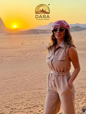 a woman standing in the desert at sunset at DARA RUM lUXURY CAMP in Wadi Rum