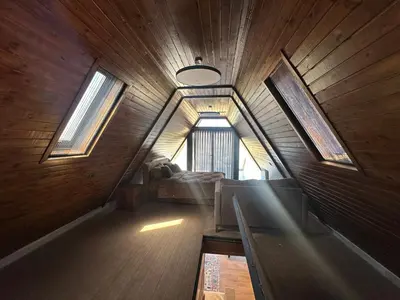an attic room with a couch and windows at Umm Aljulud Cottages 02 in Ajloun