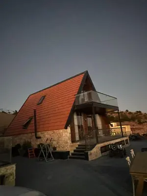a small house with a red roof and a glass at Umm Aljulud Cottages 02 in Ajloun