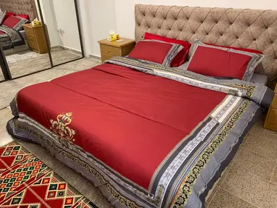 a large bed with red sheets and red pillows at City View Rooftop Apartment Amman in Amman