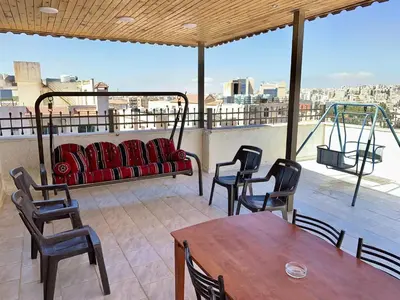 a balcony with a table and chairs and a couch at City View Rooftop Apartment Amman in Amman