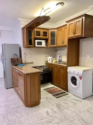 a kitchen with wooden cabinets and a washer and dryer at City View Rooftop Apartment Amman in Amman