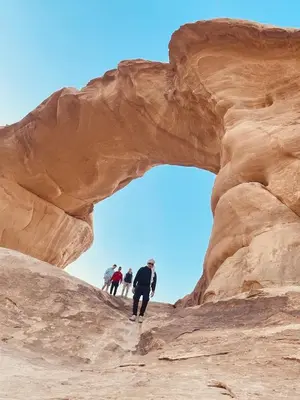 a group of people walking through an arch in the desert at Rum Desert Silence Camp in Wadi Rum