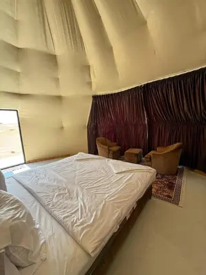 a bedroom with a white bed and two chairs at NAJMA lUXURY CAMP in Wadi Rum