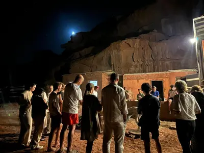 a group of people standing around at night at Fire bedouin camp in Wadi Rum