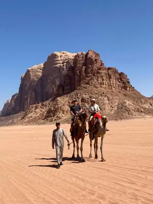 a man walking with people on horses in the desert at Rum Tale Camp in Wadi Rum