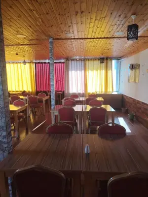 a dining room with tables and chairs and windows at Petra Bed Hostel in Petra