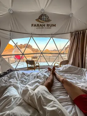 a person laying on a bed in a tent at FARAH RUM LUXURY CAMP & Bubbles Hotel in Wadi Rum
