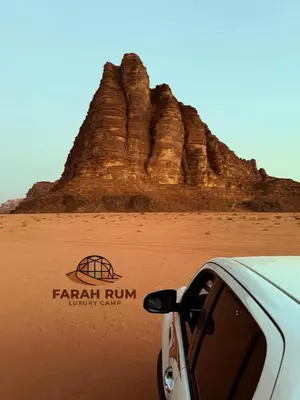 a car parked in front of a rock formation at FARAH RUM LUXURY CAMP & Bubbles Hotel in Wadi Rum