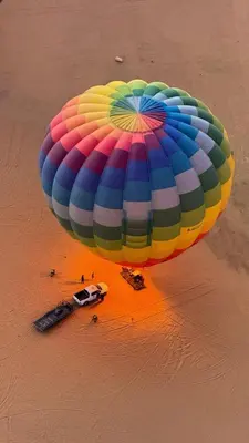 a large colorful parachute on a beach with a car at Rum Adventure Camp in Wadi Rum