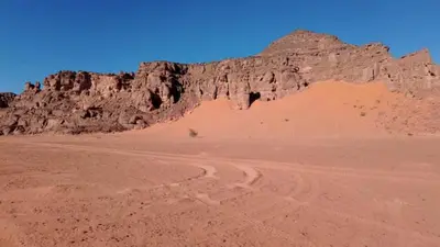 a desert with a mountain and a dirt road at Rum Adventure Camp in Wadi Rum