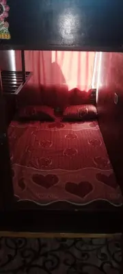 a small bed with two pillows and a red curtain at Petra sharing room in Petra