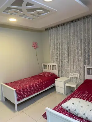 a bedroom with two beds and a flower on the wall at Al qaoud apartment in Aydūn