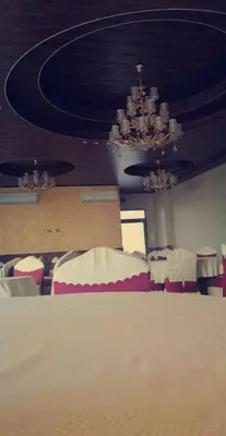 a room with tables and chairs and a chandelier at Al qaoud apartment in Aydūn