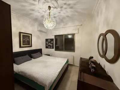 a bedroom with a bed and a chandelier at Furnished luxuries Apartment with a Stunning View in Amman