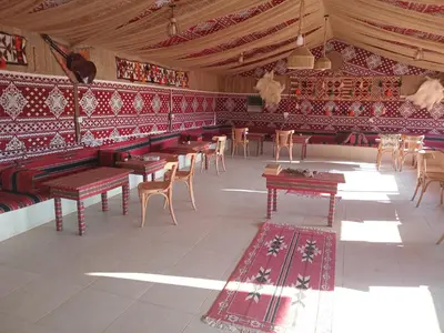 a room with tables and chairs and red walls at Ayed Wadi Rum camp in Wadi Rum