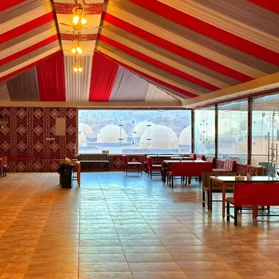 a dining room with tables and chairs and windows at Desert Oasis in Wadi Rum Village - Cozy Lodge Room in Aqaba