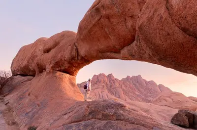 a person standing on top of a rock formation at faisal wadi rum in Wadi Rum