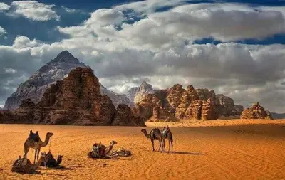 a group of people riding camels in the desert at faisal wadi rum in Wadi Rum