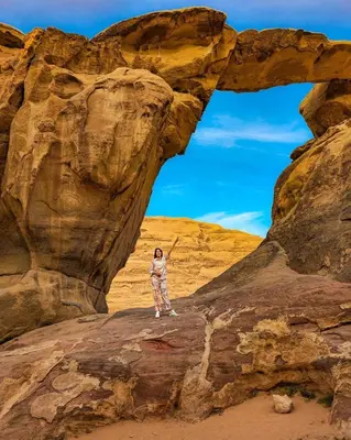 a person standing on a rock in the desert at Wadi Rum Sila Camp in Wadi Rum