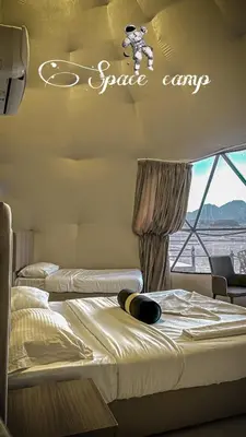 two beds in a room with a space camp sign on the wall at Wadi Rum Sila Camp in Wadi Rum
