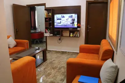 a waiting room with orange chairs and a flat screen tv at Premium apartment Section A in Wadi Musa