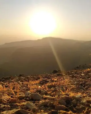 a sun setting on a rocky hill with the sun setting at Camping Guide in Dana