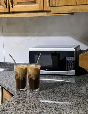two glasses of coffee on a counter next to a microwave at Miami Luxe Apartment ماركا