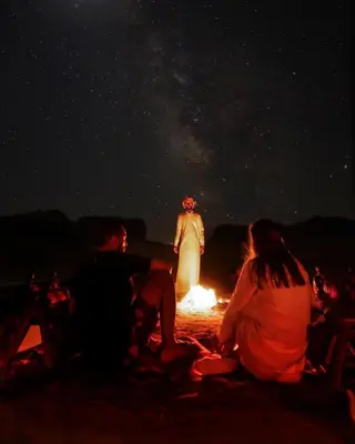 a group of people sitting around a fire at night at Nomad Heights Authentic Bedouin Cave Experience in Wadi Rum in Wadi Rum