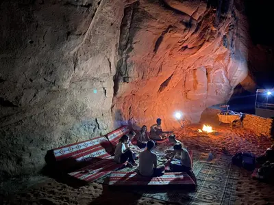 a group of people sitting on a bench in a cave at Nomad Heights Authentic Bedouin Cave Experience in Wadi Rum in Wadi Rum