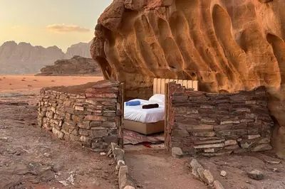 a bedroom with a bed in a rock wall at Nomad Heights Authentic Bedouin Cave Experience in Wadi Rum in Wadi Rum