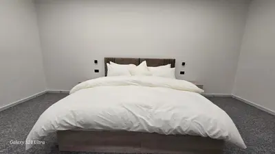 a white bedroom with a large bed with white sheets and pillows at Jeeso Hotel in Jerash