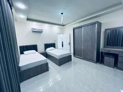 a bedroom with two beds and a fireplace at Zurich Furnished Apartments in Al Mafraq