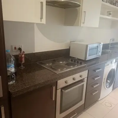 a kitchen with a stove and a microwave on a counter at Family WeekEnds Getaways at Samarah Resort Studio in Sowayma