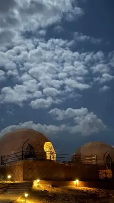 a group of domes in a field at night at Gmal Rum Cano in Wadi Rum