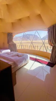 a bedroom with a bed and a large window at LAVRA lUXURY CAMP in Wadi Rum