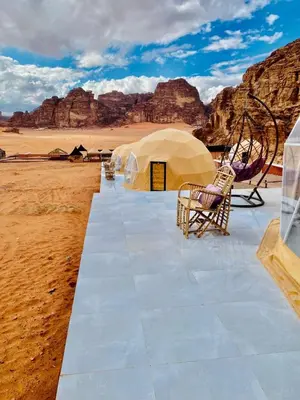 a group of tents in the desert with mountains at LAVRA lUXURY CAMP in Wadi Rum